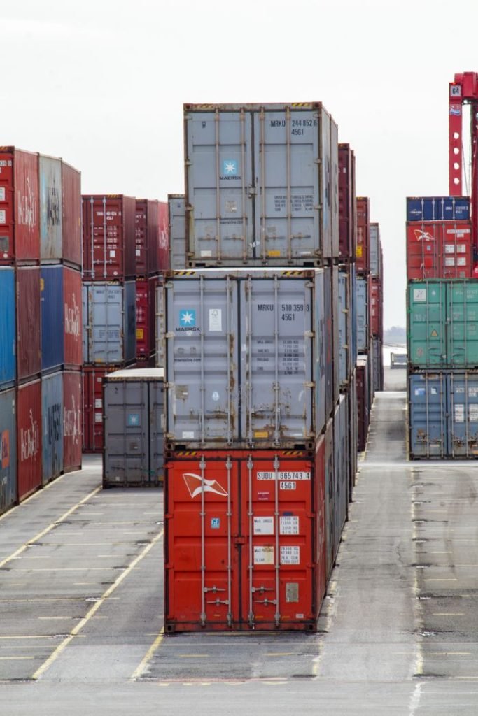 Vertical shot of colorful shipping containers stacked at an industrial port, showcasing logistics.